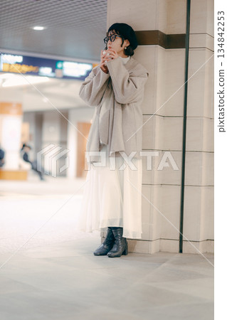 Full-body portrait of a woman in her 30s drinking coffee while waiting Full-body portrait of a woman in her 30s drinking coffee while waiting 134842253