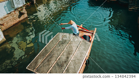 Charming boatman steering through serene waters in a traditional canoe. Zhujiajiao, Shanghai, China 134842394