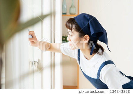 A housekeeping woman cleaning windows A housekeeping woman cleaning windows 134843838