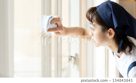 A housekeeping woman cleaning windows A housekeeping woman cleaning windows 134843841