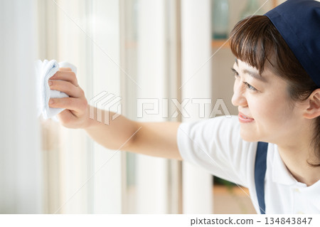 A housekeeping woman cleaning windows 134843847