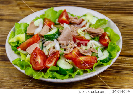 Tasty tuna salad with lettuce and fresh vegetables on wooden table 134844009