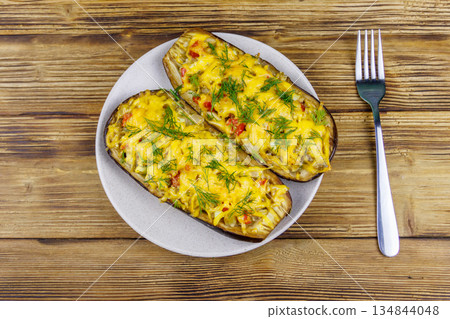 Baked stuffed eggplants on a wooden table. Top view. Healthy food and dieting concept Baked stuffed eggplants on a wooden table. Top view. Healthy food and dieting concept 134844048