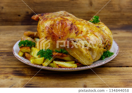 Baked whole chicken with potato on a wooden table Baked whole chicken with potato on a wooden table 134844058