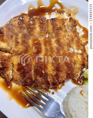 Crispy tonkatsu, a Japanese-style breaded and deep-fried pork cutlet, served with shredded cabbage and drizzled with savory sauce. A delightful balance of crunchy texture and juicy meat. Crispy tonkatsu, a Japanese-style breaded and deep-fried pork cutlet, served with shredded cabbage and drizzled with savory sauce. A delightful balance of crunchy texture and juicy meat. 134845335