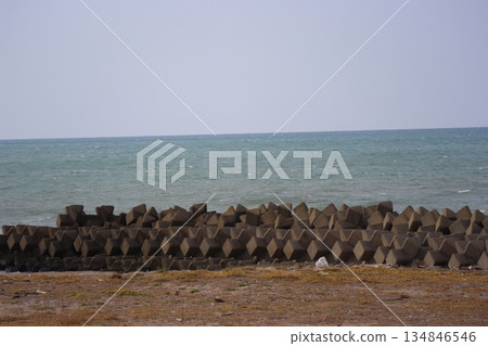 海岸風光，四腳防波堤，泛著白浪的藍色海洋，地平線和淡藍色的天空。 134846546
