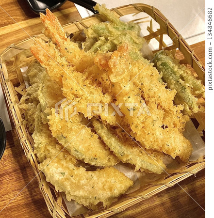 Crispy tempura with light golden batter, showcasing delicate crunchy texture and tender ingredients inside, highlighting its airy coating and appetizing appearance in close-up detail 134846682