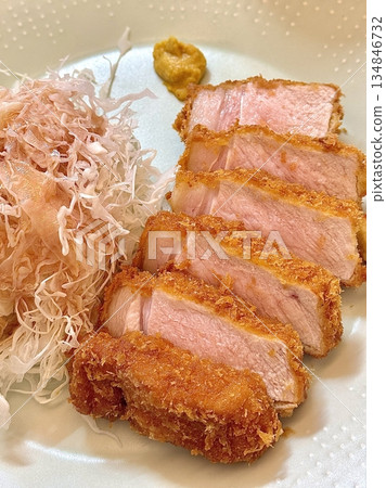 Crispy tonkatsu, a Japanese-style breaded and deep-fried pork cutlet, served with shredded cabbage and drizzled with savory sauce. A delightful balance of crunchy texture and juicy meat. Crispy tonkatsu, a Japanese-style breaded and deep-fried pork cutlet, served with shredded cabbage and drizzled with savory sauce. A delightful balance of crunchy texture and juicy meat. 134846732