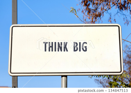 A white rectangular sign stands prominently against a clear blue sky with the inspiring words THINK BIG printed in bold letters. It inspires imagination and reaching potential A white rectangular sign stands prominently against a clear blue sky with the inspiring words THINK BIG printed in bold letters. It inspires imagination and reaching potential 134847513