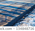 Spring thaw, a road with snow and purple transparent shadows with a fine stripe. Roadside, diagonal composition 134848716