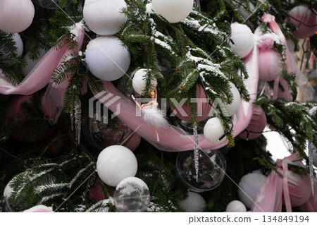 Christmas tree decorated with white baubles, ribbons, crystal icicles, small ballerina ornament on snow-dusted fir branches, creating festive mood Christmas tree decorated with white baubles, ribbons, crystal icicles, small ballerina ornament on snow-dusted fir branches, creating festive mood 134849194