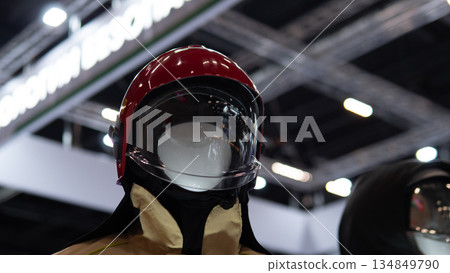 Mannequin wearing red helmet and turnout collar closeup presenting rescue uniform texture and reflective visor in exhibition setting with warm lighting and realistic service emblem details Mannequin wearing red helmet and turnout collar closeup presenting rescue uniform texture and reflective visor in exhibition setting with warm lighting and realistic service emblem details 134849790