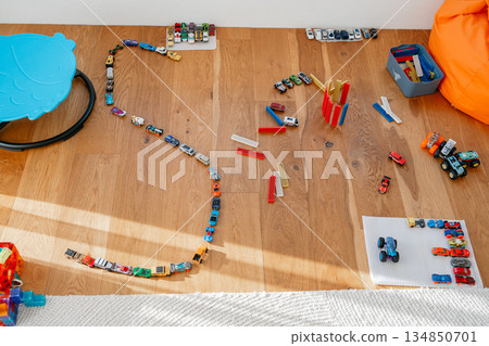 Bright assortment of colorful building toys spread across a wooden floor. Blocks, tracks and elements create a playful creative scene perfect for themes of childhood development, playtime, imagination 134850701