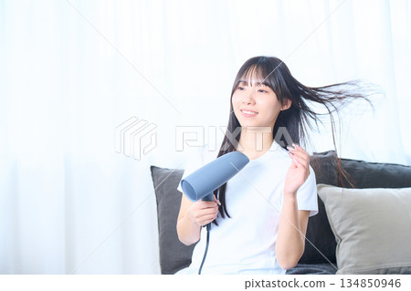 一位日本女性在明亮的客廳使用吹風機 134850946