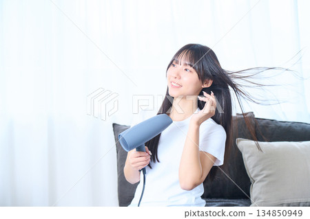 一位日本女性在明亮的客廳使用吹風機 134850949