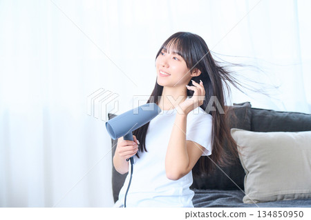 一位日本女性在明亮的客廳使用吹風機 134850950