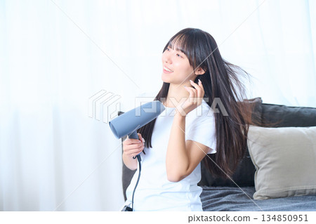 一位日本女性在明亮的客廳使用吹風機 134850951