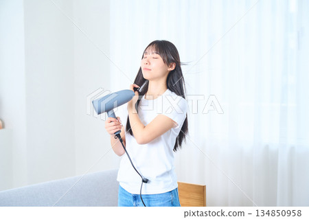 一位日本女性在明亮的客廳使用吹風機 134850958
