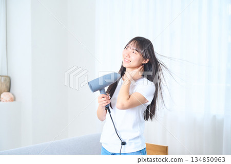 一位日本女性在明亮的客廳使用吹風機 134850963
