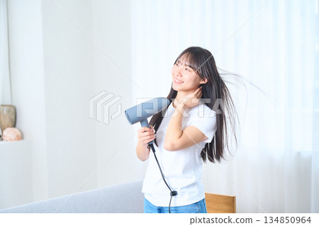 一位日本女性在明亮的客廳使用吹風機 134850964