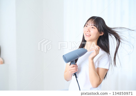 一位日本女性在明亮的客廳使用吹風機 134850971