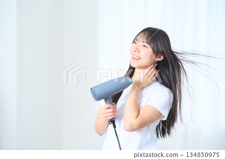 一位日本女性在明亮的客廳使用吹風機 134850975