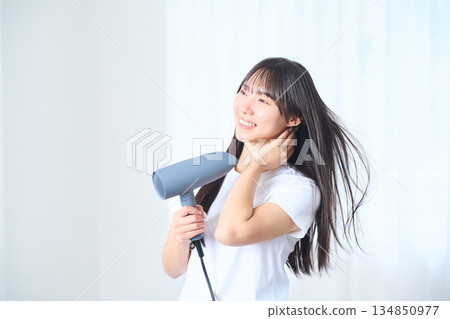 一位日本女性在明亮的客廳使用吹風機 134850977