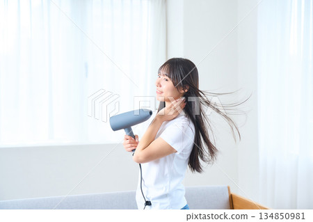 一位日本女性在明亮的客廳使用吹風機 134850981