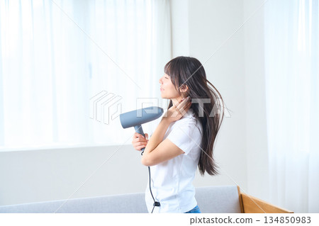 一位日本女性在明亮的客廳使用吹風機 134850983