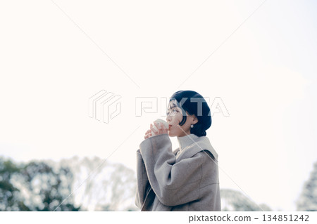 Lifestyle portrait of a woman in her 30s drinking coffee outdoors Lifestyle portrait of a woman in her 30s drinking coffee outdoors 134851242