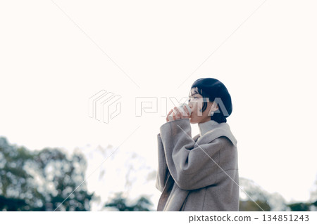 Lifestyle portrait of a woman in her 30s drinking coffee outdoors 134851243
