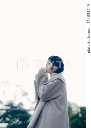 Lifestyle portrait of a woman in her 30s drinking coffee outdoors Lifestyle portrait of a woman in her 30s drinking coffee outdoors 134851249