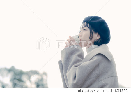 Lifestyle portrait of a woman in her 30s drinking coffee outdoors Lifestyle portrait of a woman in her 30s drinking coffee outdoors 134851251