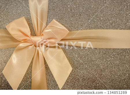 Close-up of a luxury gift box with a shiny silver glitter texture and an elegant satin ribbon bow. Close-up of a luxury gift box with a shiny silver glitter texture and an elegant satin ribbon bow. 134851289
