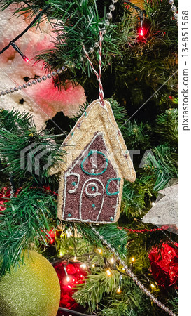 Close-up of a Christmas tree decorated with a white angel figurine, red beads and warm fairy lights. Close-up of a Christmas tree decorated with a white angel figurine, red beads and warm fairy lights. 134851568