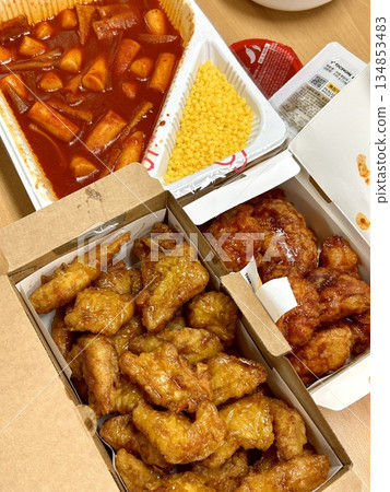 Crispy Korean fried chicken with golden coating served alongside spicy tteokbokki with chewy rice cakes in rich red sauce, creating a flavorful combination of crunchy and savory textures 134853483