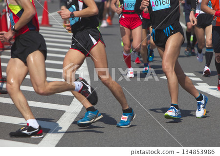 The dynamic movement of the feet and running shoes of amateur runners running smoothly in a marathon 134853986