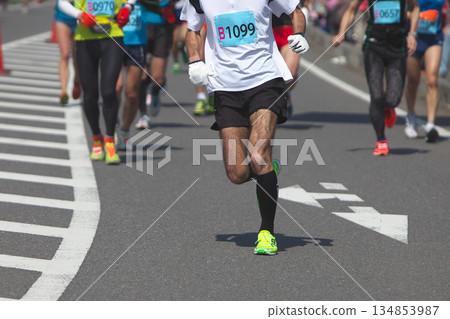 The dynamic movement of the feet and running shoes of amateur runners running smoothly in a marathon 134853987