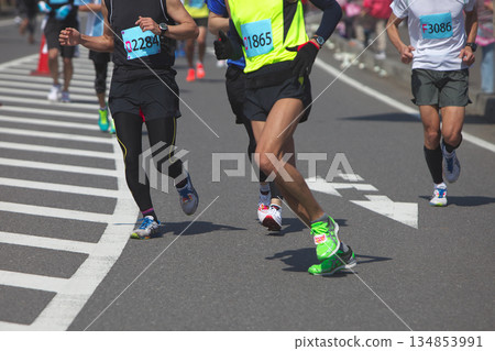 當業餘跑者在馬拉鬆比賽中流暢奔跑時,腳部和跑鞋的動態運動 當業餘跑者在馬拉鬆比賽中流暢奔跑時,腳部和跑鞋的動態運動 134853991