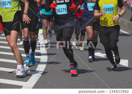 The dynamic movement of the feet and running shoes of amateur runners running smoothly in a marathon 134853992