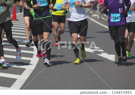 The dynamic movement of the feet and running shoes of amateur runners running smoothly in a marathon 134853993