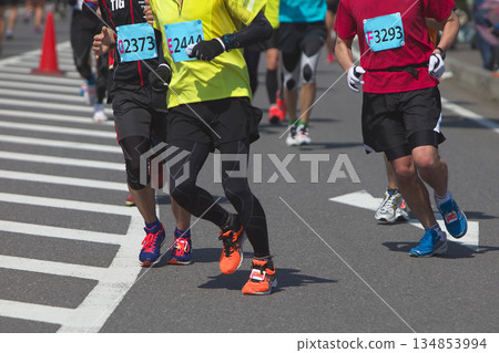 The dynamic movement of the feet and running shoes of amateur runners running smoothly in a marathon 134853994