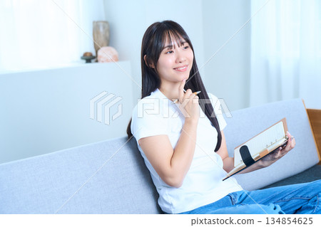 一位日本女性打開筆記本,思考著…(畫面內容:想法、未來計畫與學習) 一位日本女性打開筆記本,思考著…(畫面內容:想法、未來計畫與學習) 134854625