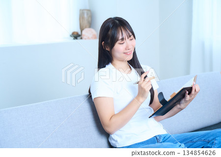 A Japanese woman opening a notebook and thinking Image of ideas, future plans, and studying 134854626