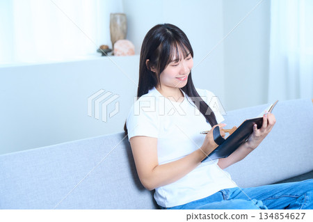 A Japanese woman opening a notebook and thinking Image of ideas, future plans, and studying 134854627