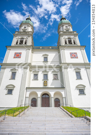 St. Lorenz Basilica stands majestically in Kempten, Bavaria, showcasing its stunning baroque architecture against a clear blue sky. The well-maintained steps invite visitors to explore its beauty. St. Lorenz Basilica stands majestically in Kempten, Bavaria, showcasing its stunning baroque architecture against a clear blue sky. The well-maintained steps invite visitors to explore its beauty. 134854813