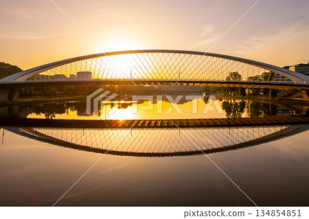 Troja Bridge stands over the Vltava River in Prague as the sun rises. The sky brightens with colors reflecting on the water below. A new day begins in this beautiful city. Troja Bridge stands over the Vltava River in Prague as the sun rises. The sky brightens with colors reflecting on the water below. A new day begins in this beautiful city. 134854851