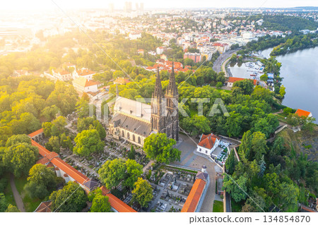 Vysehrad Basilica of St. Peter and St. Paul stands proudly in Prague, bathed in the warm glow of the sunrise. The surrounding greenery enhances its architectural beauty, creating a picturesque scene. Vysehrad Basilica of St. Peter and St. Paul stands proudly in Prague, bathed in the warm glow of the sunrise. The surrounding greenery enhances its architectural beauty, creating a picturesque scene. 134854870