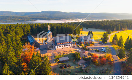 Kralovka Lookout Tower stands tall in the Jizera Mountains, surrounded by vibrant autumn foliage. Visitors can enjoy stunning views and the peaceful nature of the area. 134854941