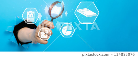 Human hand breaking through paper holding a magnifying glass analyzing business data represented by various icons, symbolizing data analysis, business strategy, and growth opportunities Human hand breaking through paper holding a magnifying glass analyzing business data represented by various icons, symbolizing data analysis, business strategy, and growth opportunities 134855076